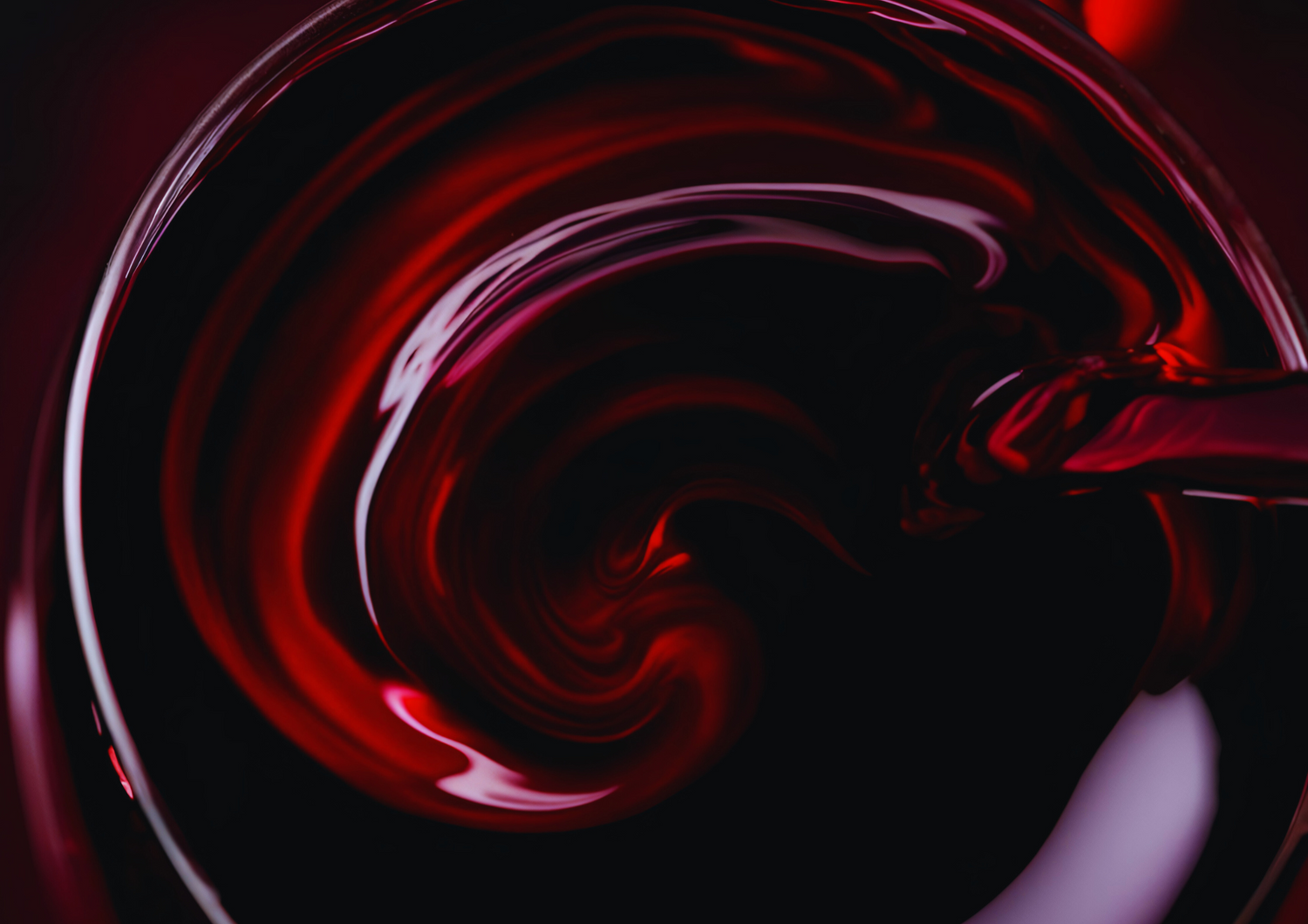 Tiefroter Wein wird in ein Glas gegossen und bildet sanfte Wirbel im Licht.