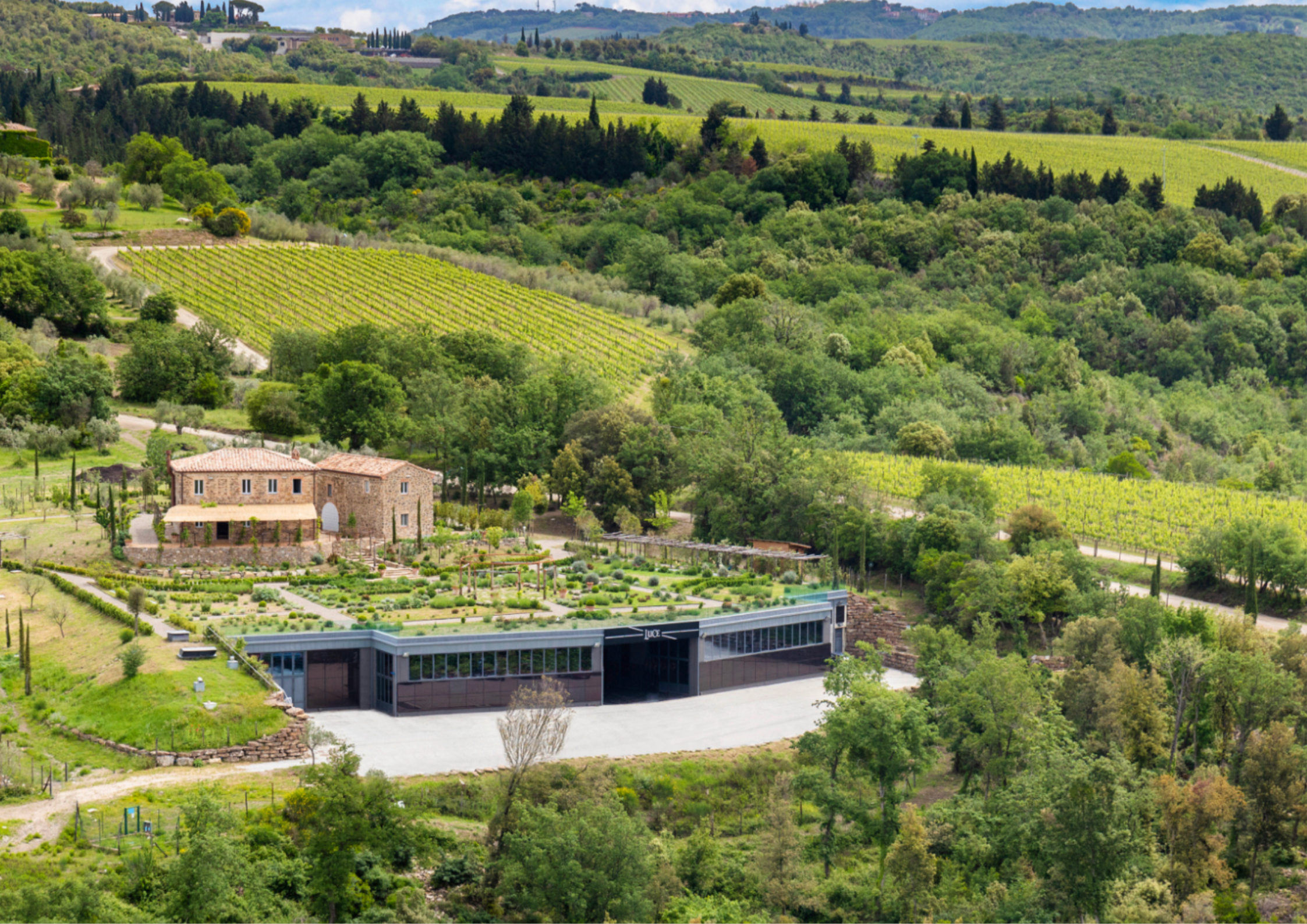 Modernes Weingut inmitten grüner Hügel und Weinrebenlandschaft in der Toskana.