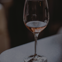 „Glas Roséwein mit zart lachsfarbener Tönung vor dunklem Hintergrund“