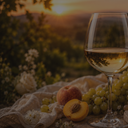„Glas Weißwein mit hellen Trauben, Pfirsich und Blüten im warmen Abendlicht“