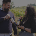 „Zwei Personen mit griechischen Weinflaschen in einem Weinberg“
